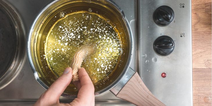 imagem com uma pessoa fazendo frituras em uma frigideira usando o truque para deixar qualquer frigideira antiaderente