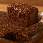 Fatia de bolo de chocolate sendo retirada da travessa