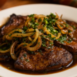 Bife de fígado acebolado servido no prato.