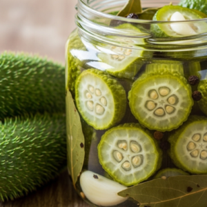 Picles de maxixe no pote com pimenta e alho. Maxixes ao lado.